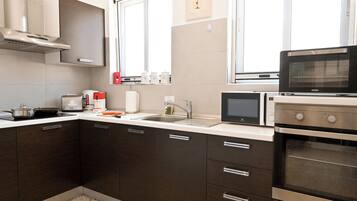 Una cocina moderna con armarios oscuros, una campana extractora de acero inoxidable, un microondas y un horno.
