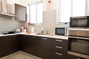 A modern kitchen with dark cabinets, a stainless steel range hood, a microwave, and an oven. - Exceptional Sea View Apart St Paul's Bay (St. Paul's Bay)