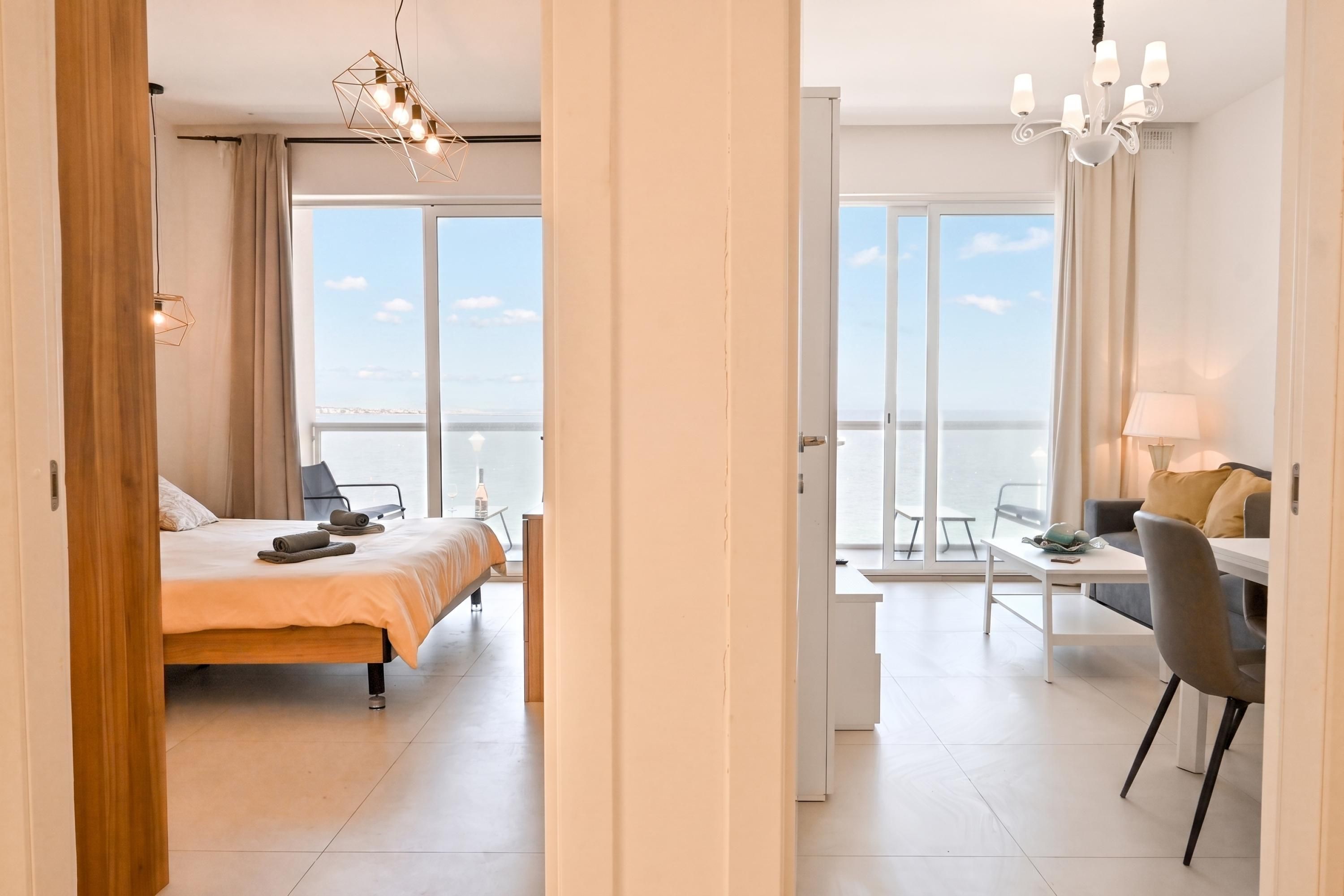 Habitación de hotel con cama, escritorio, una silla y vista al mar.