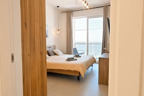 Ein Schlafzimmer mit Bett, Schreibtisch, Stuhl und Meerblick.