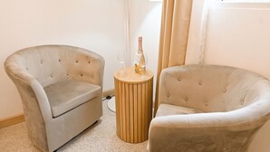 Two upholstered armchairs, a wooden side table with a bottle and glass, and a floor lamp in a room with a window and curtains. - Exceptional Sea View Apart St Paul's Bay (St. Paul's Bay)