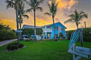 A two-story house with a blue exterior, surrounded by a well-maintained lawn and palm trees. - Private Beach Compound (Fort Pierce)