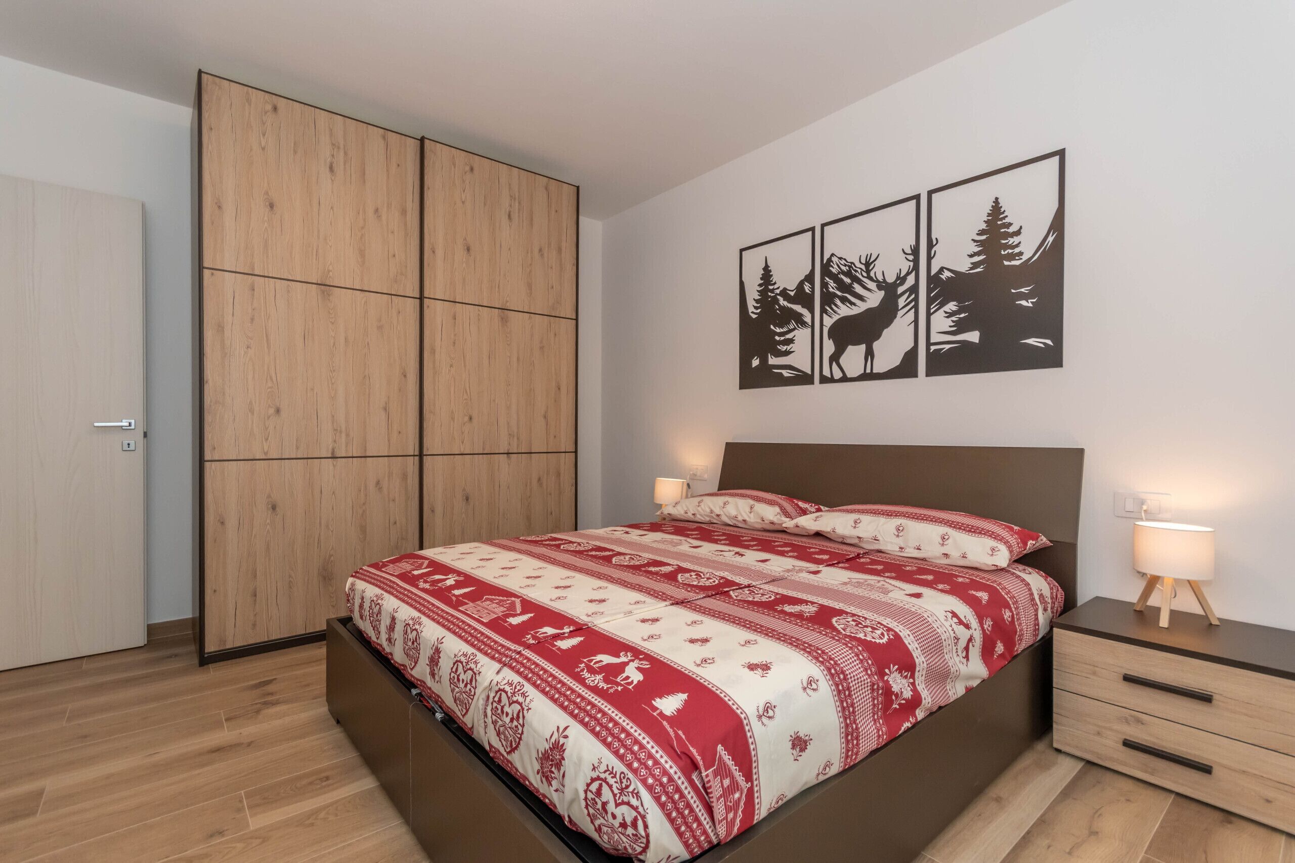 Een slaapkamer met een bed, een houten garderobe, nachtkastjes en decoratie aan de muur.