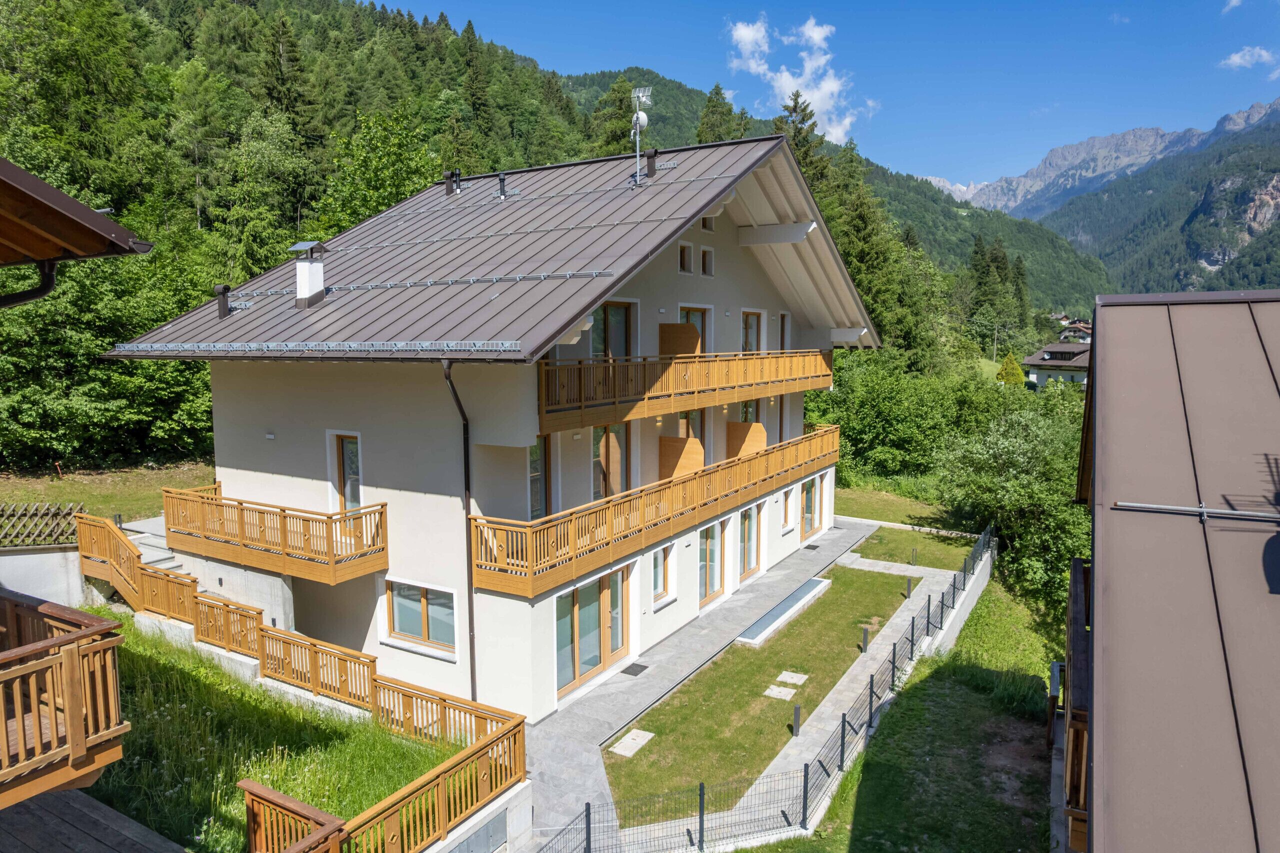 A two-story building with balconies, a sloped roof, and a view of a mountainous landscape.