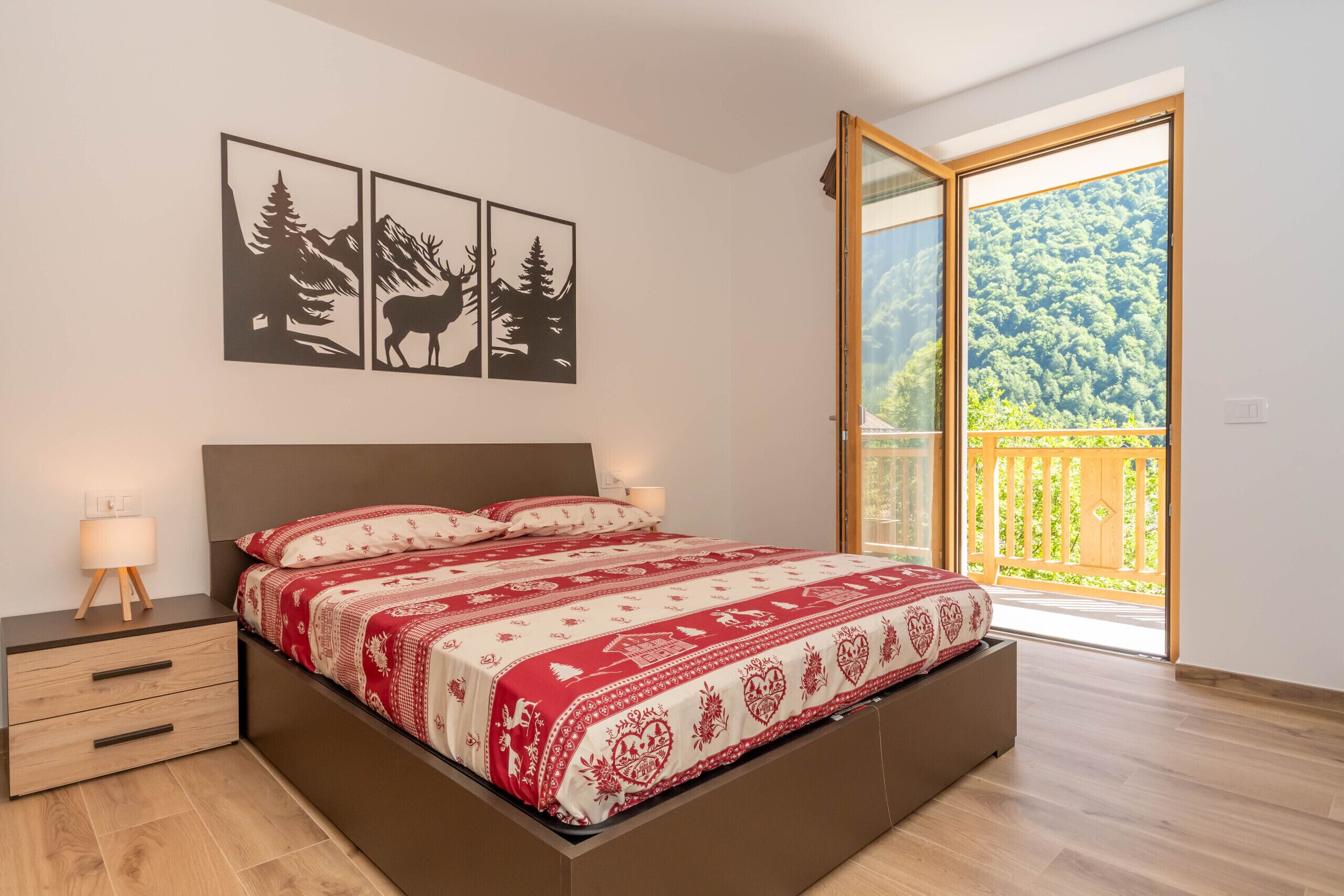 Un dormitorio con cama, mesitas de noche y un amplio ventanal con vistas al paisaje verde.