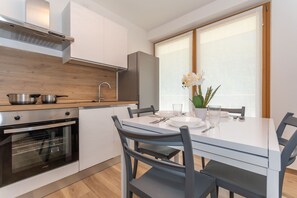 Een moderne keuken met een inbouwoven, een roestvrijstalen koelkast en een eettafel met stoelen.
