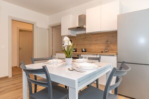 Une cuisine moderne avec des meubles blancs, une cuisinière encastrée et un réfrigérateur.