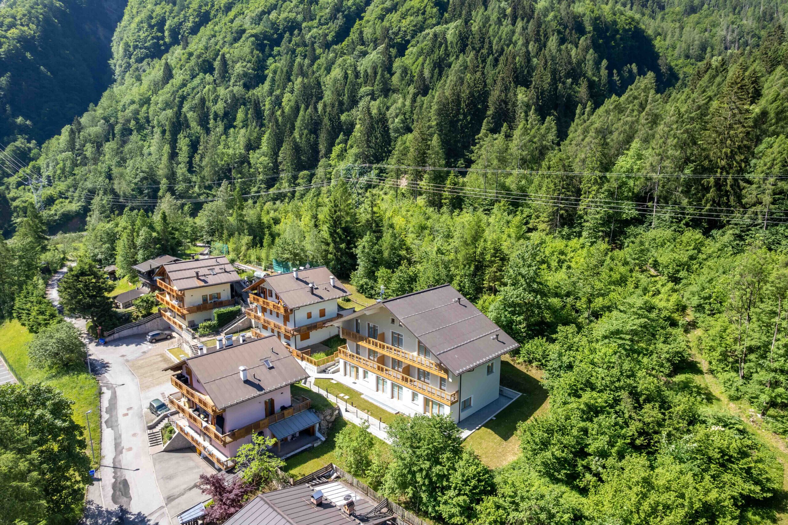 Et hotel med flere etager og balkoner, omgivet af tæt skov.
