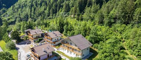 Et hotel med flere etager og balkoner, omgivet af tæt skov.