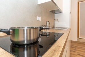Una cocina moderna con una olla de acero inoxidable sobre una cocina por inducción, un lavamanos y encimeras de madera.