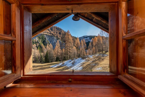 A wooden cabin with a triangular roof and a view of a mountainous landscape.
