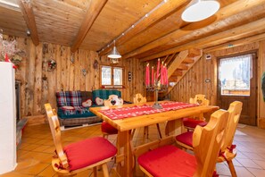 Ein Holzinterieur mit einem Esstisch, Stühlen, einer Couch und einer Treppe.