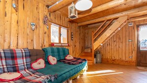 A cozy wooden cabin interior with a sofa, a staircase, and a lantern.