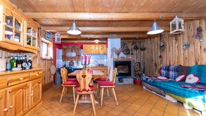 A wooden interior with a dining table, chairs, a sofa, and a fireplace.