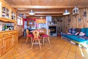 Ein Holzinnenraum mit Esstisch, Stühlen, einer Couch und einem Kamin.