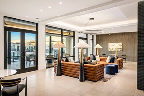 Ein modernes Wohnzimmer mit Ledersofas, Stehlampen und einem großen Fenster mit Blick auf eine Stadtlandschaft.