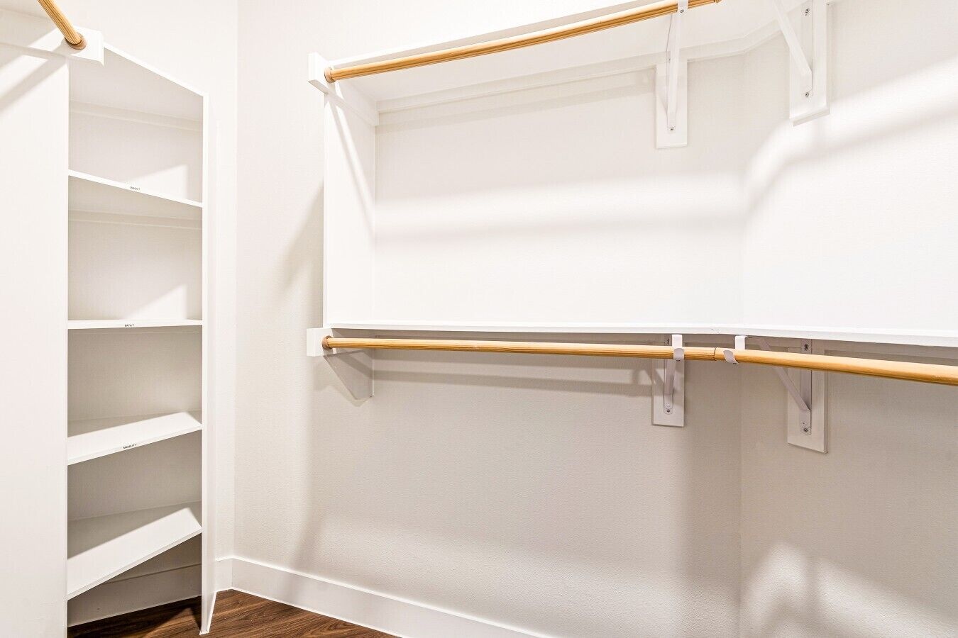 A white closet with open shelves and a wooden rod.