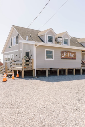 A two-story building with a wooden deck, a sign reading 'JP's Wharf,' and a gravel driveway.