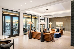 Eine moderne Hotelhalle mit Sitzgelegenheiten, großen Fenstern und Blick auf die Stadt.