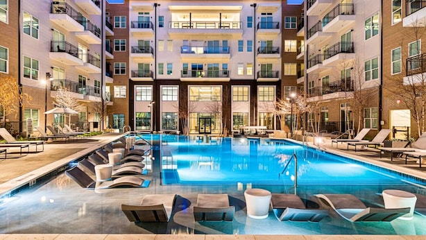 A multi-story building with a central pool area, lounge chairs, and a no-diving sign. - C.R.E.A.M & Cocoa | Resort Pool, Laundry, Parking (Dallas)