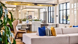A modern interior with a sofa, chairs, a desk, and large windows. - C.R.E.A.M & Cocoa | Resort Pool, Laundry, Parking (Dallas)