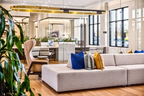 Ein modernes Interieur mit einer Couch, Sesseln, einem Schreibtisch und großen Fenstern.