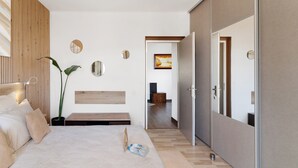 A modern bedroom with a bed, bedside tables, a potted plant, and a wooden headboard.