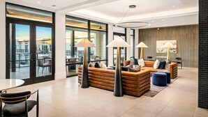 Ein modernes Wohnzimmer mit Ledersofas, einem Essbereich und großen Fenstern mit Blick auf die Stadt.
