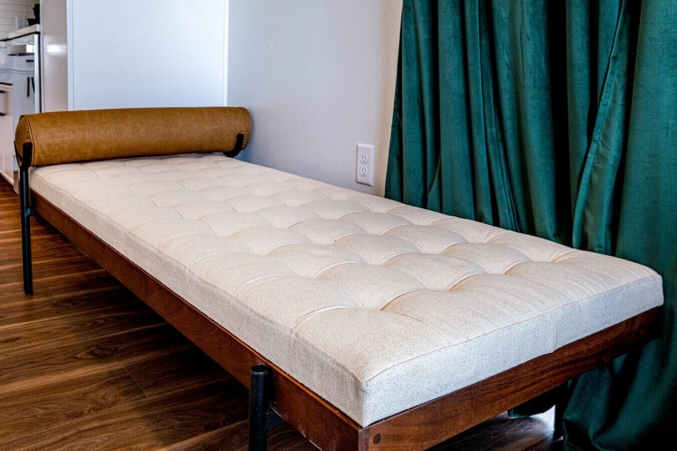 A single bed with a wooden frame and a mattress with a textured top.