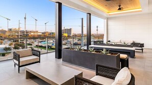 Eine moderne Lounge mit Blick auf die Stadt, ausgestattet mit einer Couch, einer Bank und einem Pflanzgefäß mit Pflanzen.