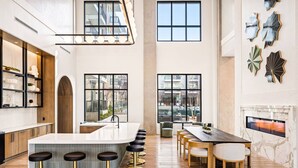 Een moderne keuken met een centraal eiland, barstoelen en een zithoek met een open haard.