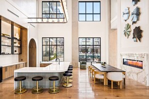 A modern kitchen with a central island, bar stools, and a dining area with a fireplace. - Obsidian Opulence | Resort Pool, Laundry, Parking (Dallas)