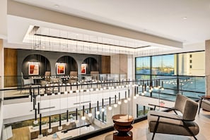 Eine moderne Hotelhalle mit Glastrennwand, Sitzgelegenheiten und Blick auf die Stadt.