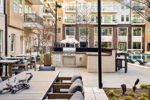 An outdoor patio area with tables and chairs, a grill station, and a pool. - Lavish Gold Apt | Resort Pool, Laundry, Parking (Dallas)