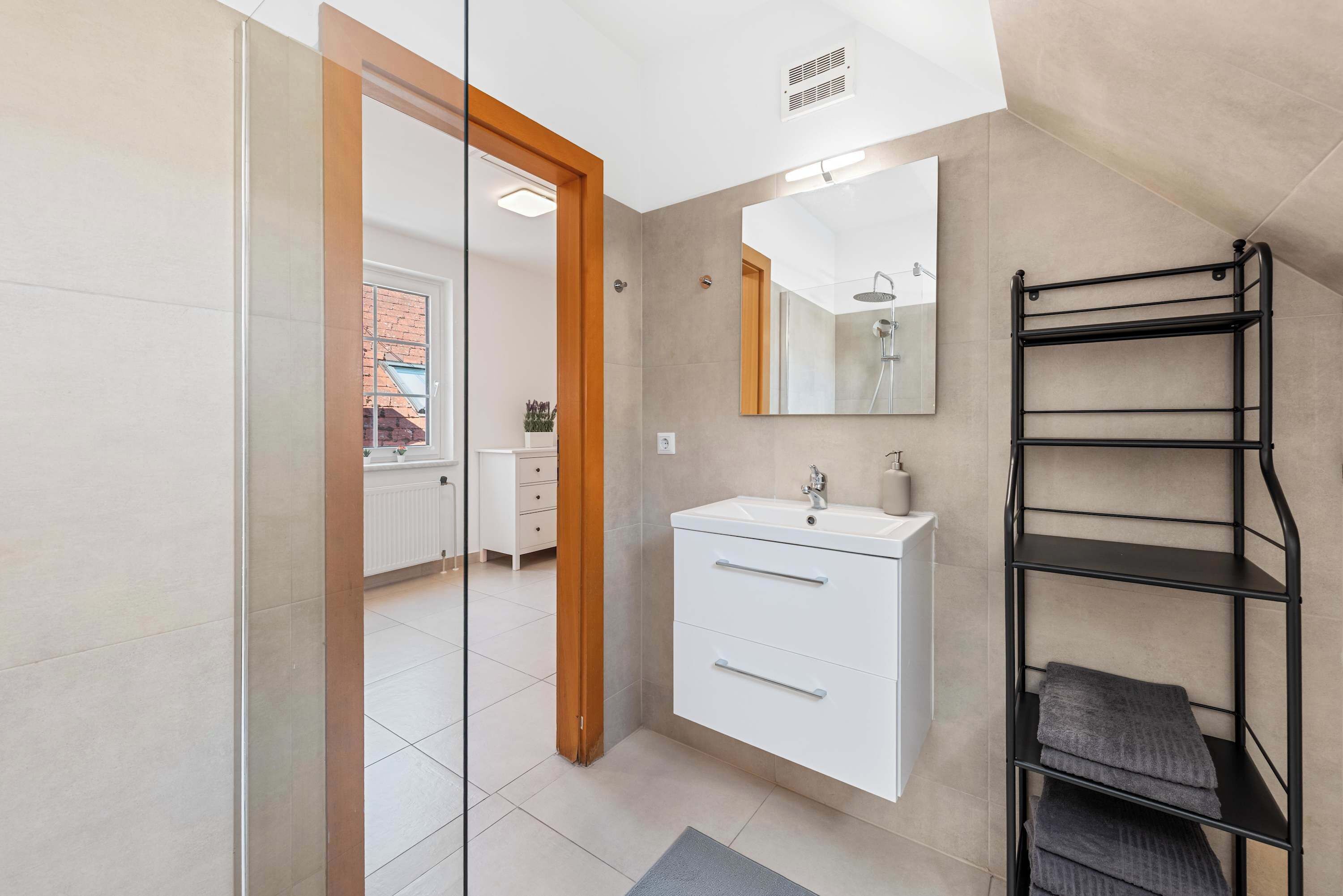 Une salle de bain moderne avec un meuble-lavabo blanc, un miroir et un porte-serviettes noir.