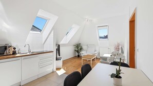Una cocina moderna con armarios blancos, encimera de madera y microondas integrado.