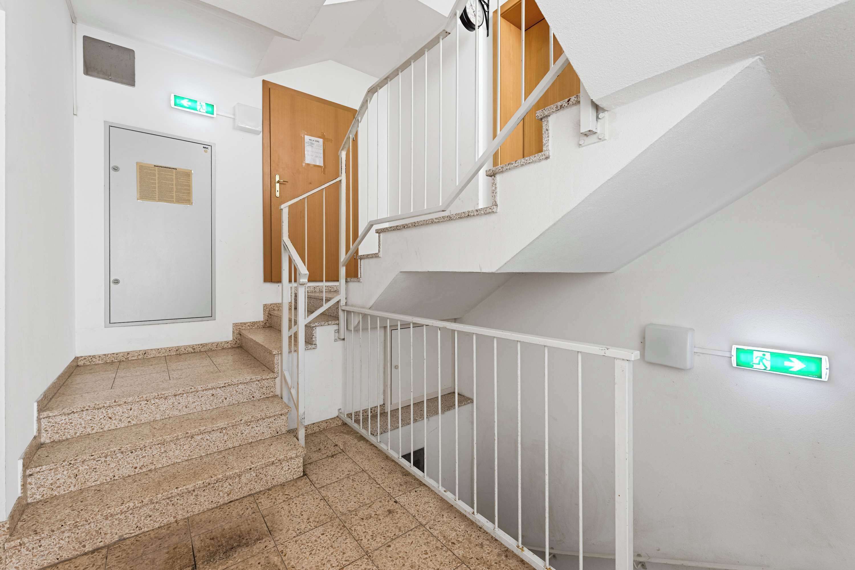 Un escalier avec des rampes blanches et une porte en bois.