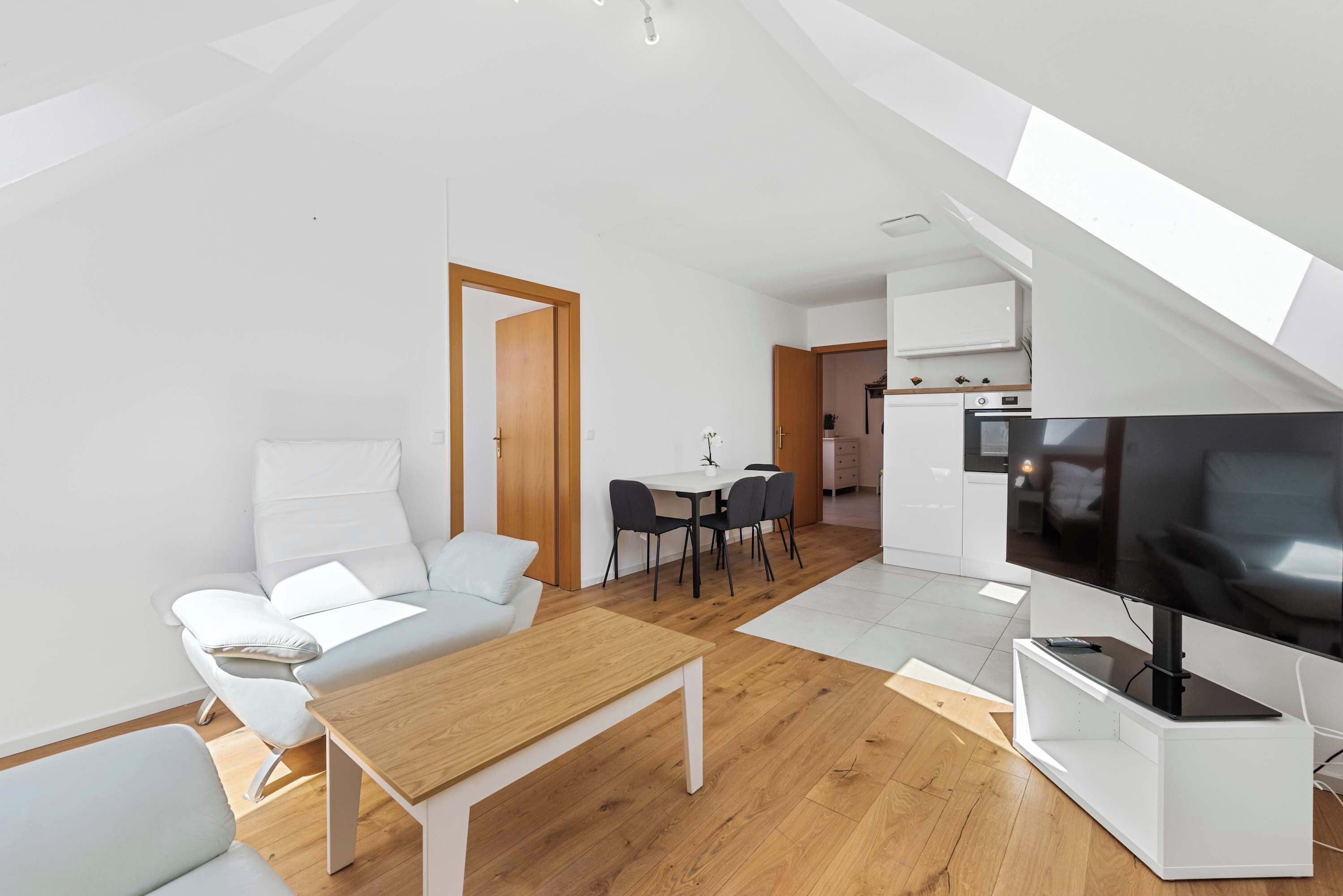 Un apartamento moderno con comedor, sofá, televisor y cocina.