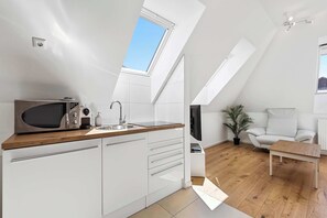 Una cucina moderna con un lucernario, mobili bianchi, un forno a microonde e un lavandino.