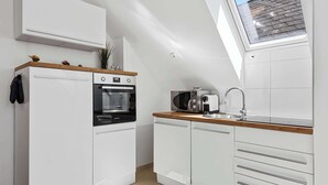 Una cocina moderna con armarios blancos, horno empotrado, microondas y fregadero.