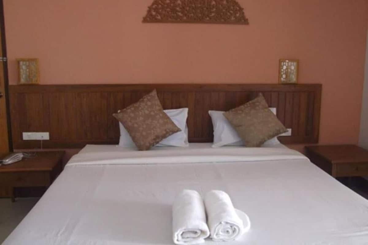 A neatly made bed with pillows, a wooden headboard, and a wall-mounted decorative piece.