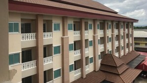 A multi-story hotel with balconies, a flat roof, and a view of the surrounding area. - Butnamtong Hotel (Lampang)