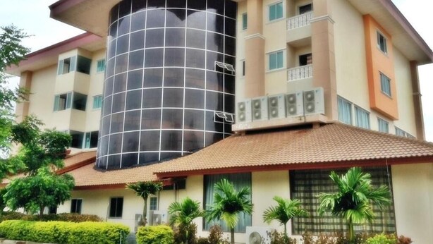A multi-story building with a prominent cylindrical glass structure, balconies, and a tiled roof. - Butnamtong Hotel (Lampang)
