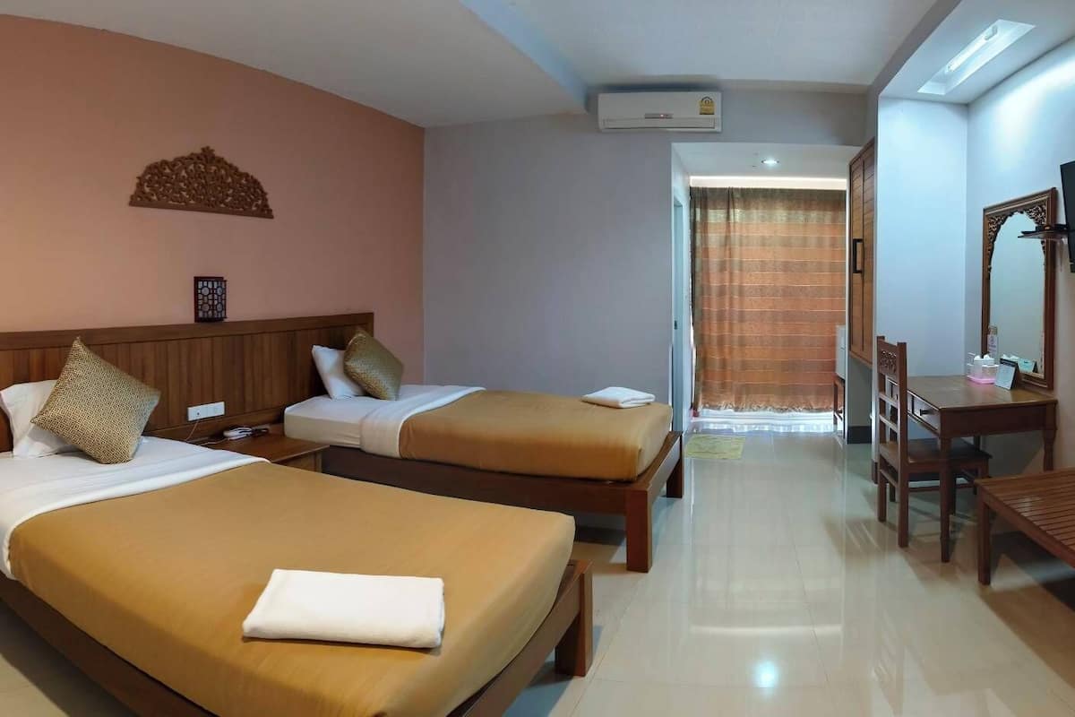 A hotel room with two beds, a desk, a chair, a television, and a mirror.