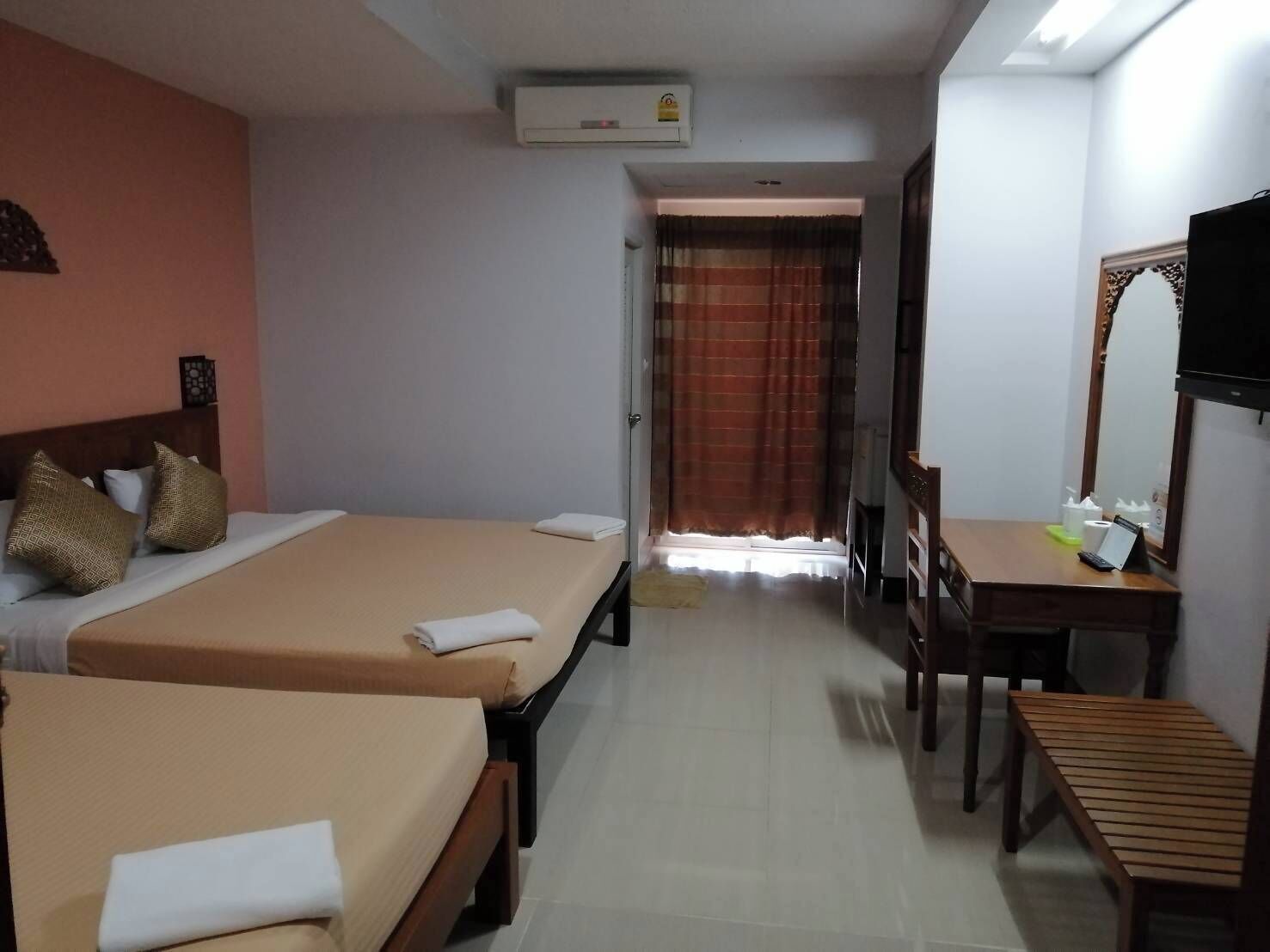 Camera d'albergo con due letti, una scrivania, una sedia, un televisore e un condizionatore.