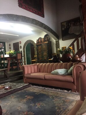 A cozy living room with a sofa, a patterned rug, and a green door. - Furnished chalet with pool and fireplace in the center of Serra Negra. (Serra Negra)