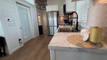 A modern kitchen with a stainless steel refrigerator, a marble countertop, and a built-in oven.