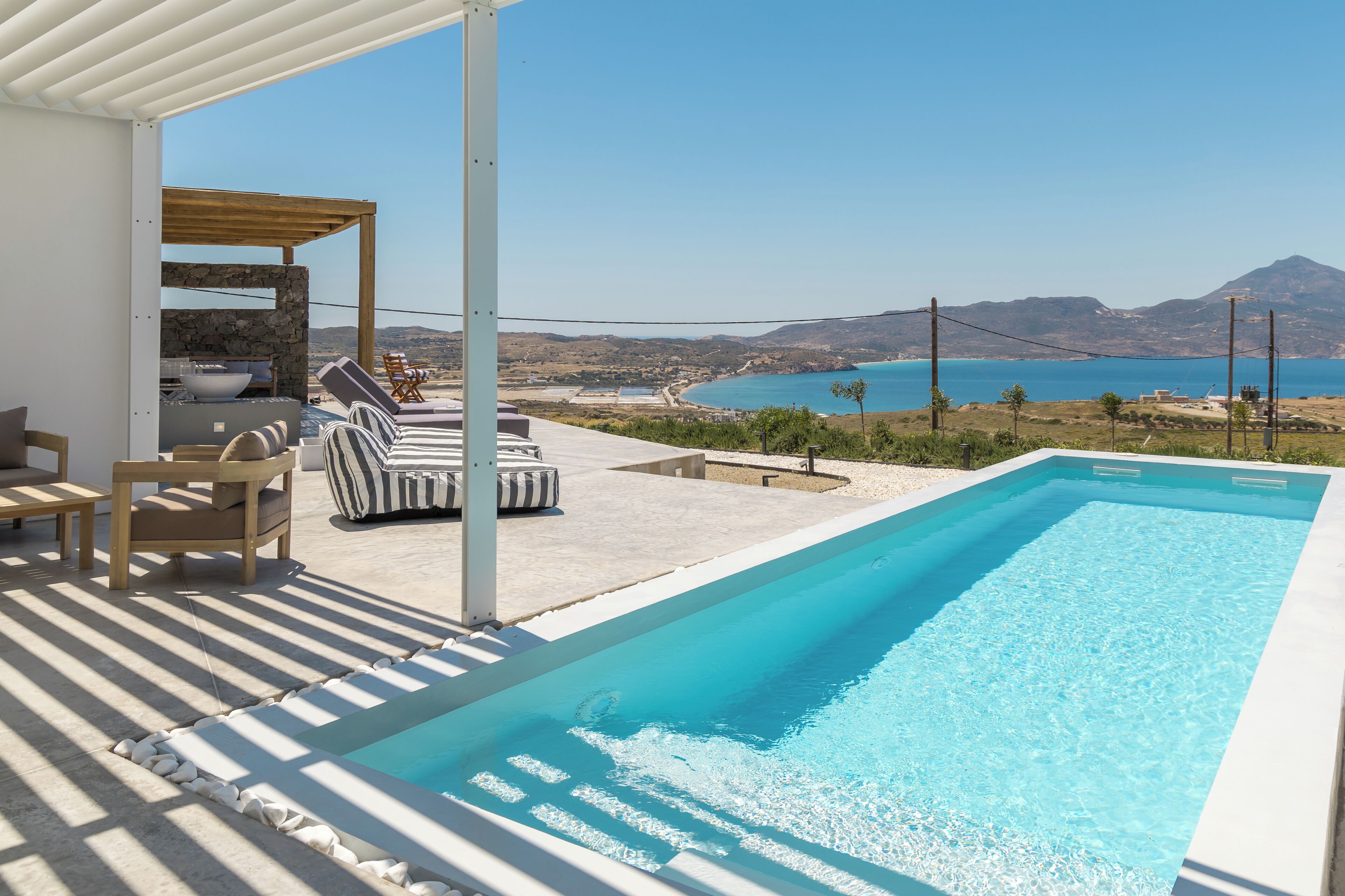 Una piscina con vistas al mar, sillas de descanso y una estructura de piedra.