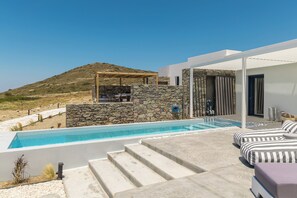A modern outdoor pool area with a stone wall, a pergola, and a lounge with striped cushions. - Villa Nabia II, Seaview and Sunset view, Private Pool (Adamas)