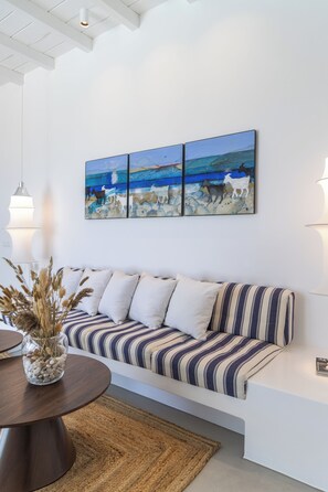 A modern living room with a striped sofa, a round coffee table, and a wall-mounted painting. - Villa Nabia II, Seaview and Sunset view, Private Pool (Adamas)